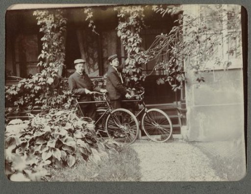 Two boys with bicycles in front of a house