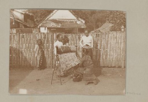 Woman working batik with onlookers