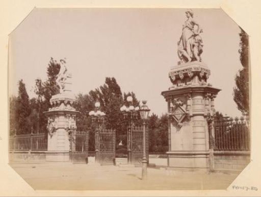 Entrance with a fence and two pillars with sculptures