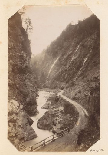 Road with tunnel next to a body of water near rocks