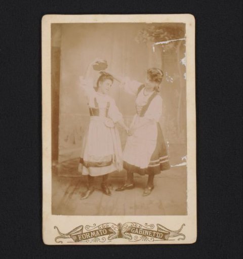 Two girls in traditional dress with a tambourine