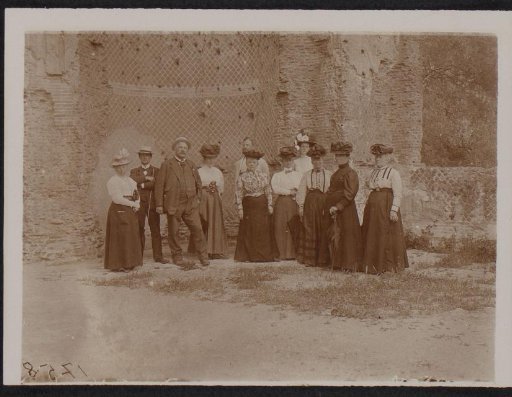 Group portrait of men and women before a ruin (possibly) in Italy