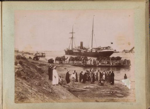 View of a landing place at Kantara on the Suez Canal with a ship, men and camels on vessels