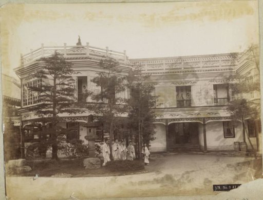Geishas posing in front of and on the gallery of a house in Japan