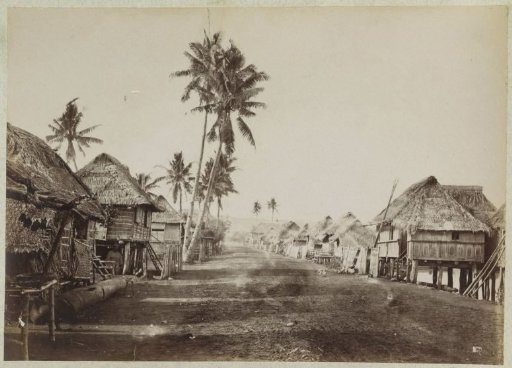Village street with houses with thatched roofs, possibly in the Philippines