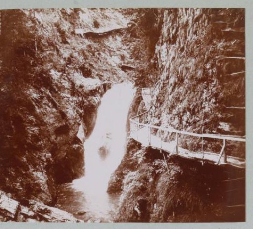 Waterfall in the Alps with a Mountain Path Beside It