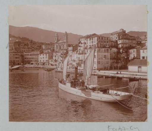 View of Bastia with a sailing boat in the harbor in the foreground and the St. Jean Baptiste in the background