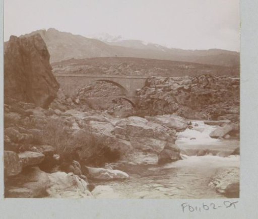 View of a river in Corsica with a double-arched bridge