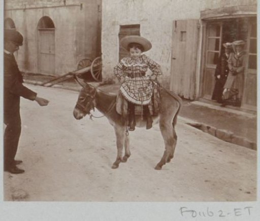 Girl in a checkered dress sitting on an ass in the street, presumably in Southern France