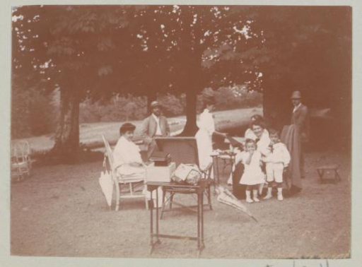 Group of men, women and children sitting under trees, probably in Italy or France