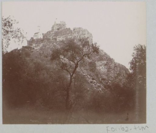 View of a mountain peak with a church and a ruin, presumably in Southern France