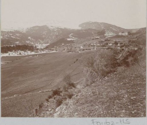 Mountain landscape with fields, houses and snow-capped peaks, presumably in Southern France