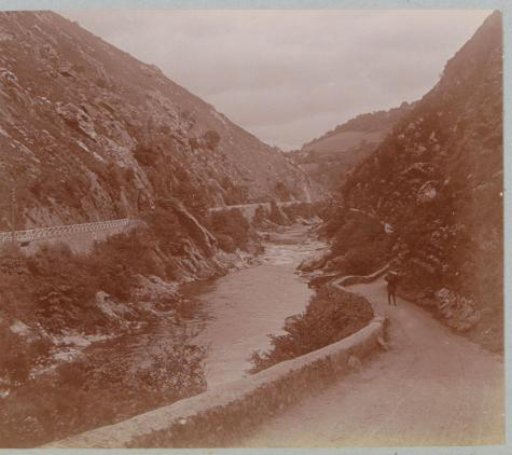 Mountain landscape with a stream, a road and a pedestrian, probably in France