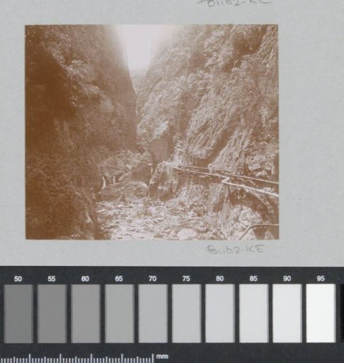 Mountain gorge with a walker on a plank on the right, probably in the Pyrenees