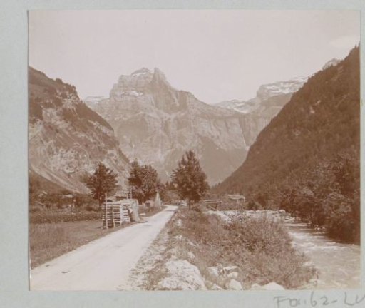 Mountain landscape with bare peaks, waterfalls, a stream and a woodpile in the Alps