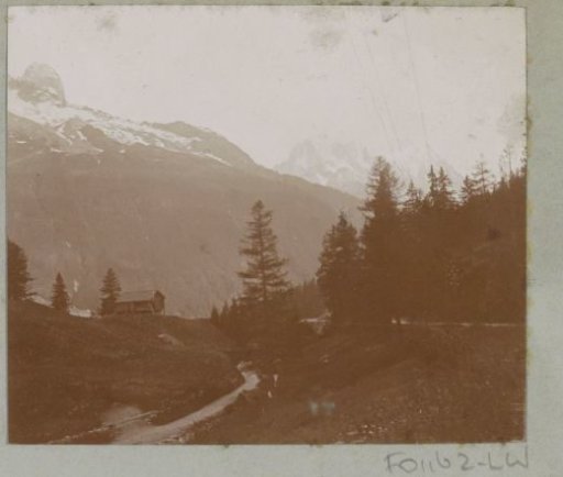 Mountain landscape with a road, a house and snow-capped mountain peaks in the Alps