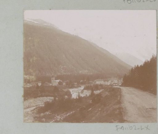 View of a village in the Alps with a road and a dry streambed in the foreground