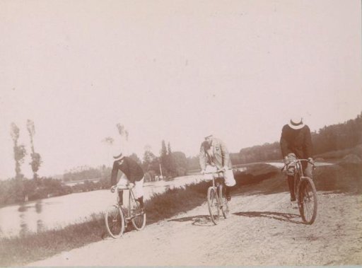 Three men on bicycles along a river at Pontoise