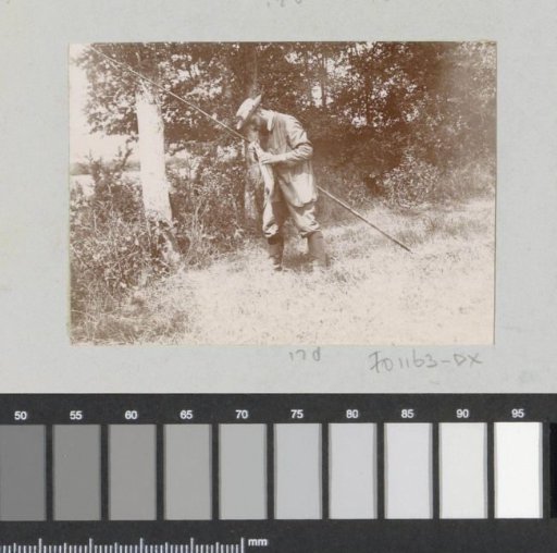 Fisherman removing caught fish from the hook, probably near Pontoise