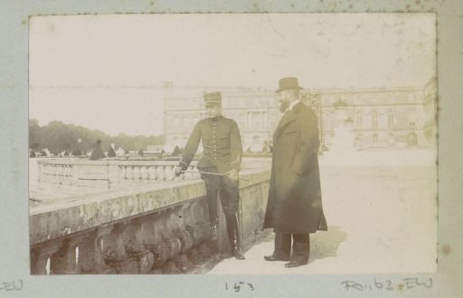 Two men, one in uniform, in a park, possibly Versailles