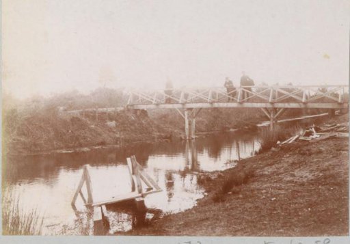 Three people on a bridge over a ditch in France