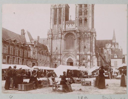 Market in Lisieux with stalls, vendors, customers, and the cathedral in the background