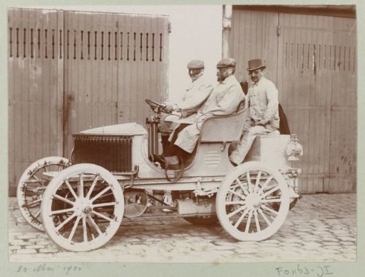Three men with goggles in an automobile, presumably in France