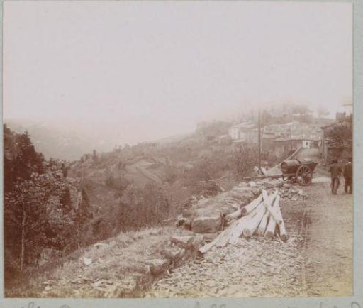 View of Saint-Privat-d'Allier with wooden poles and a cart with barrels in the foreground