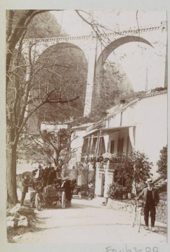 Street Scene with Cyclist and Automobile in Pont du Loup, with a Viaduct in the Background