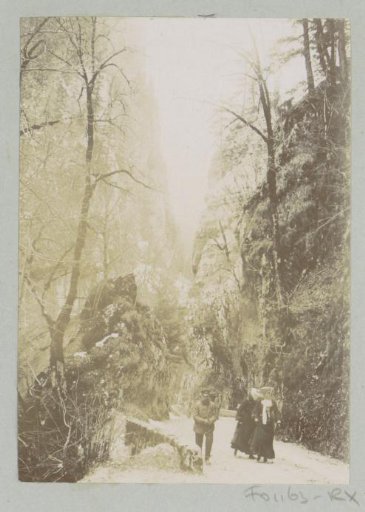 Three people walking on a mountain road, probably on the Route de la Grande Chartreuse