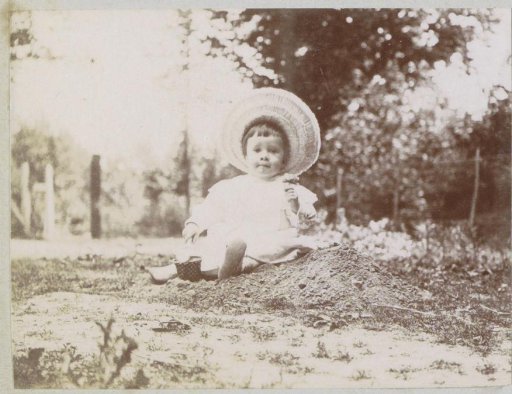Portrait of a toddler playing with a shovel and mold, probably in France