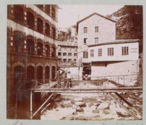 Houses, bridge and waterfall in Thiers with a car repair business on the right