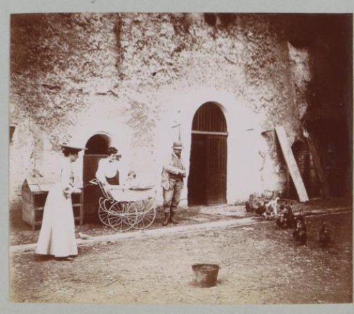 Group with a pram on a courtyard (designated 'La Charpenterie'), presumably at a country house or castle in France