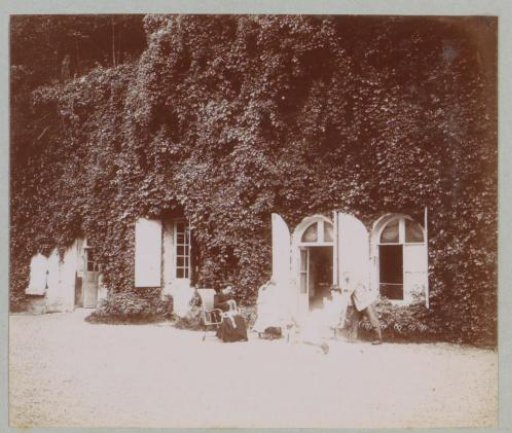 Group seated on a courtyard (designated 'La Charpenterie'), presumably at a country house or castle in France