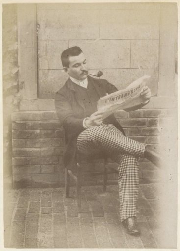 Portrait of a seated French man with a pipe and checkered trousers, reading the newspaper 'L'Intransigeant'