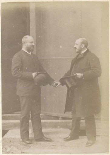 Portrait of two French men with hats, standing hand in hand in front of a metal vat