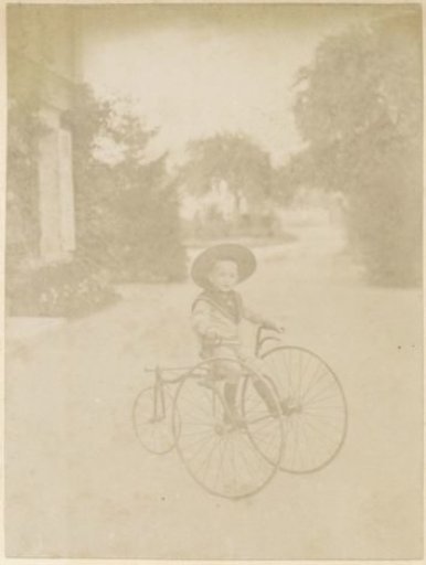 Boy riding a tricycle in a garden in France