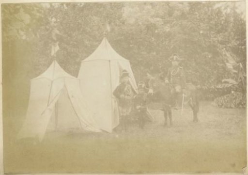 Three children playing 'soldier' in a garden in France