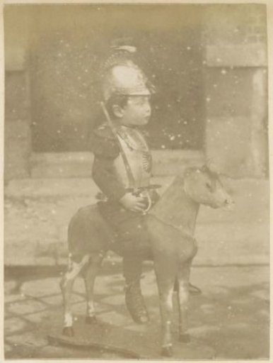 Portrait of a French boy in armor sitting on a toy horse