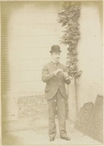 Portrait of a French man with a bowler hat, lighting a cigarette