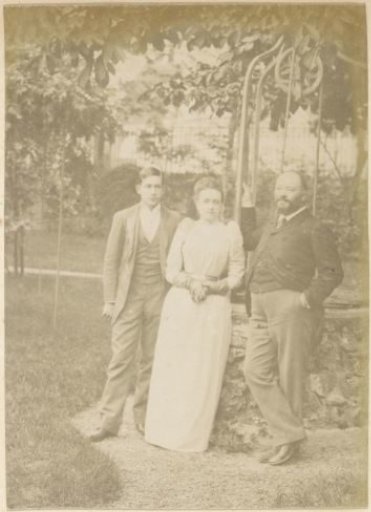 Group portrait of a woman and two men standing by a well in France