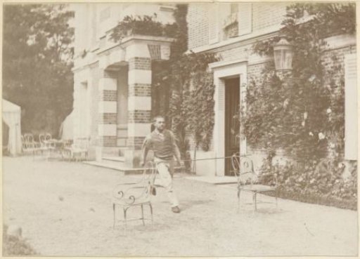 French man jumping over a stick between two chairs in a garden
