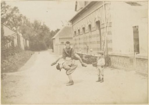 Three boys playing 'tag' (jumping) on a yard in France