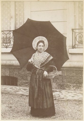 Portrait of a French woman in traditional dress with shawl, basket and umbrella