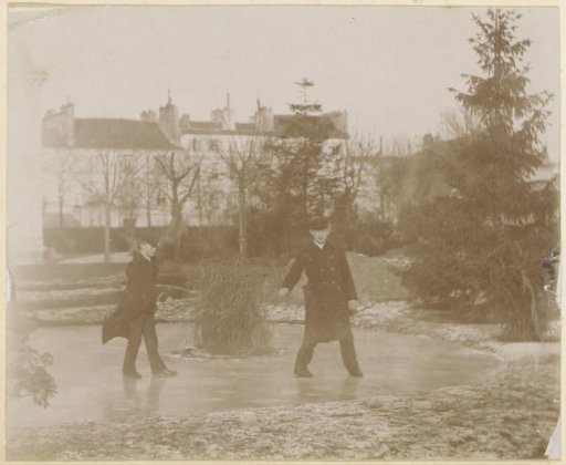 Two men in long coats skating on a pond in a garden in France