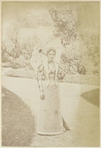 Portrait of a French woman with an umbrella on a garden path