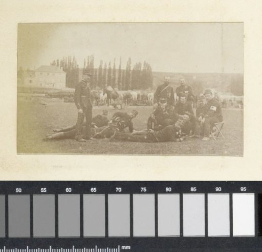 Group of soldiers posing on a grassy field in France, with horses in the background