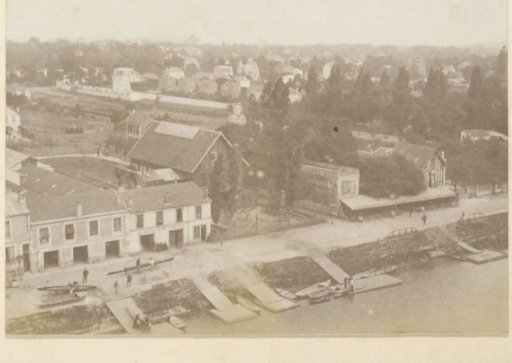 Aerial view of a quay with rowing boats, sheds, a restaurant, garage E. Mathias and houses in France