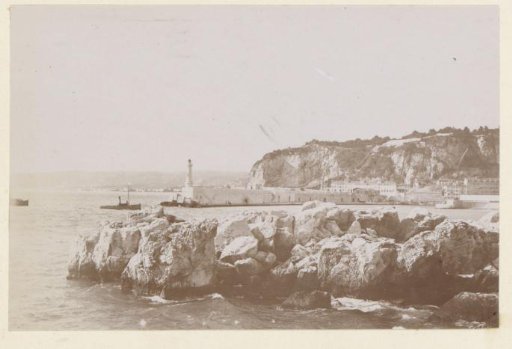 View of a harbor entrance with a lighthouse, probably on the coast of Southern France