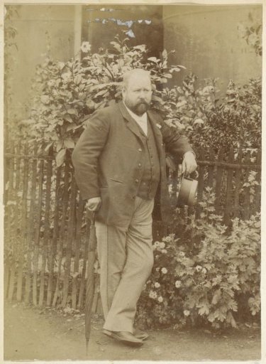 Portrait of a Man with an Umbrella and Hat in Hand, Standing by a Gate in France